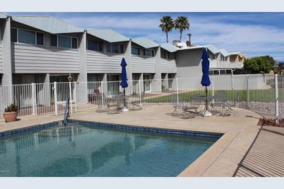 A pool with chairs and umbrellas in the background.