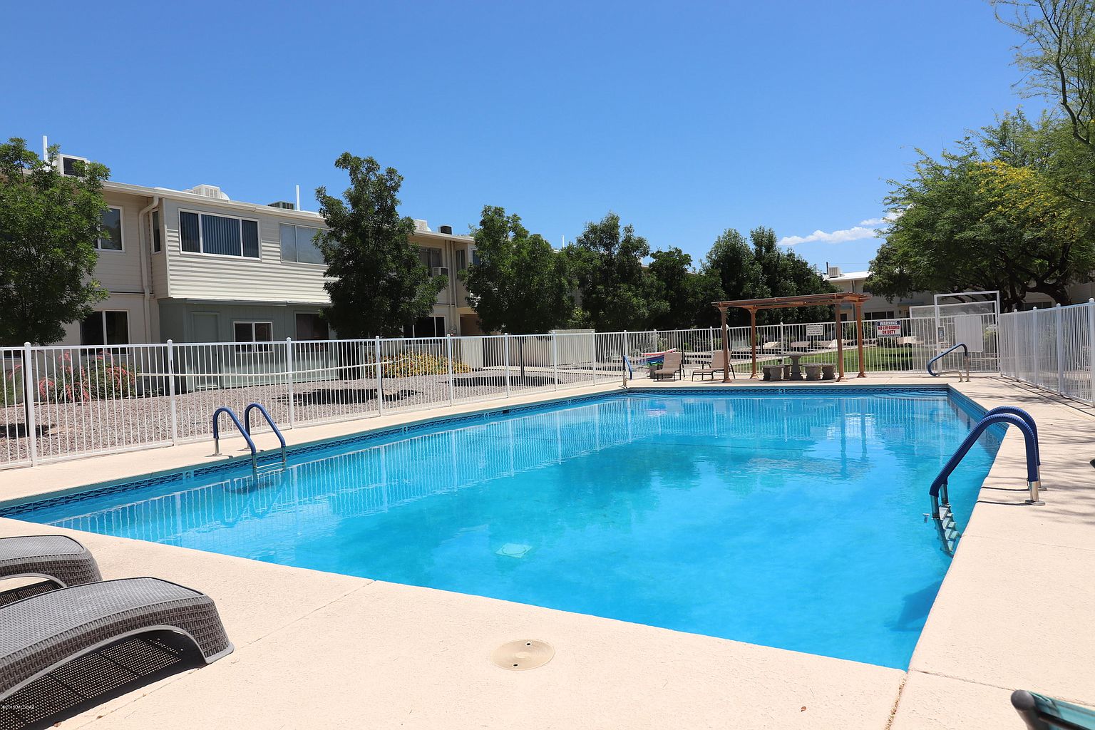 A pool with chairs and umbrellas in the background.